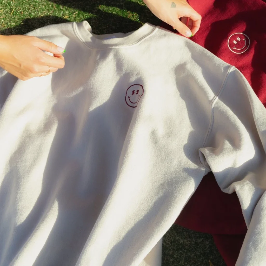 Cream sweatshirt with a burgundy smiley embroidered on the chest